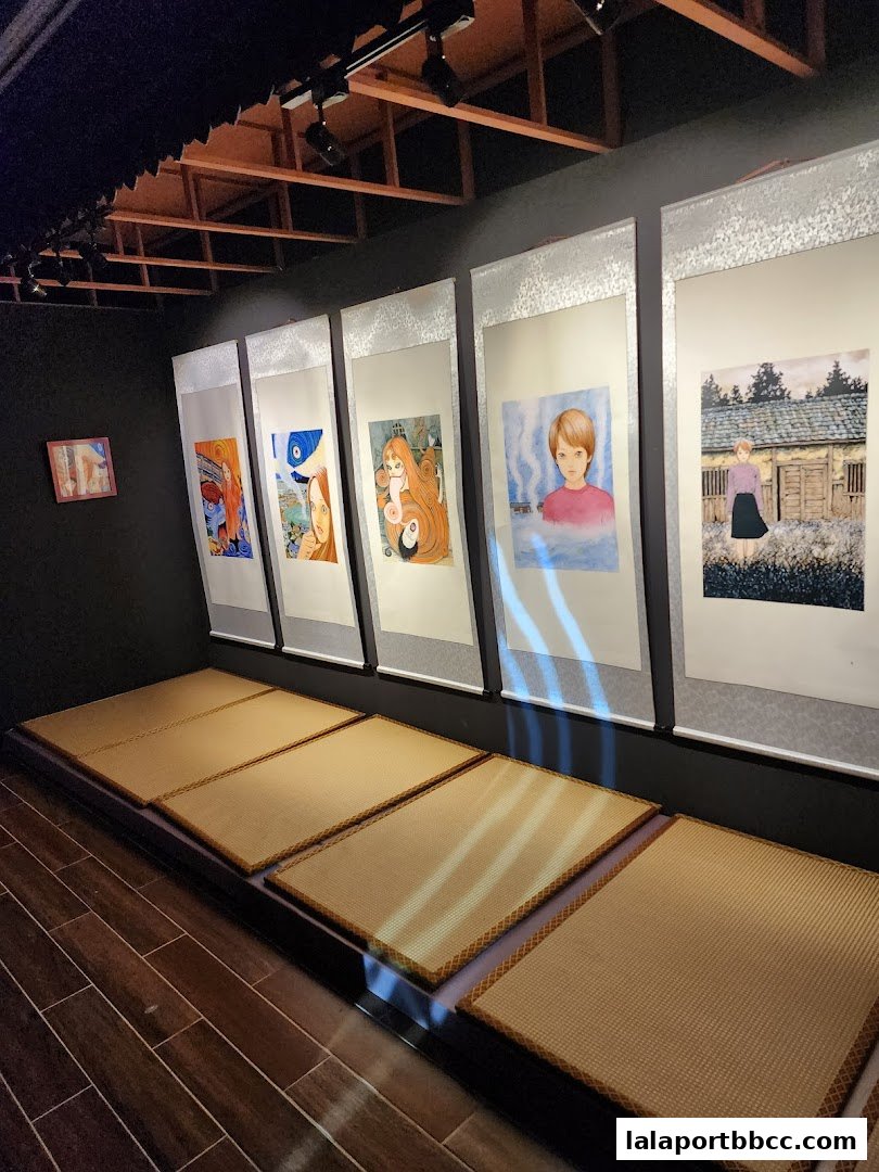 Artistic scrolls featuring Junji Ito's horror manga displayed in a dimly lit exhibition space.