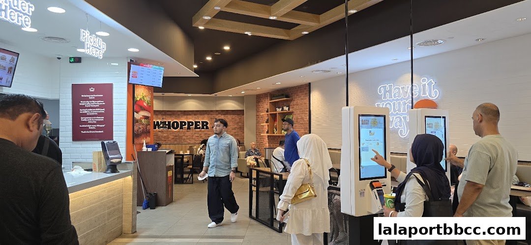 Customers ordering at self-service kiosks inside a Burger King restaurant.