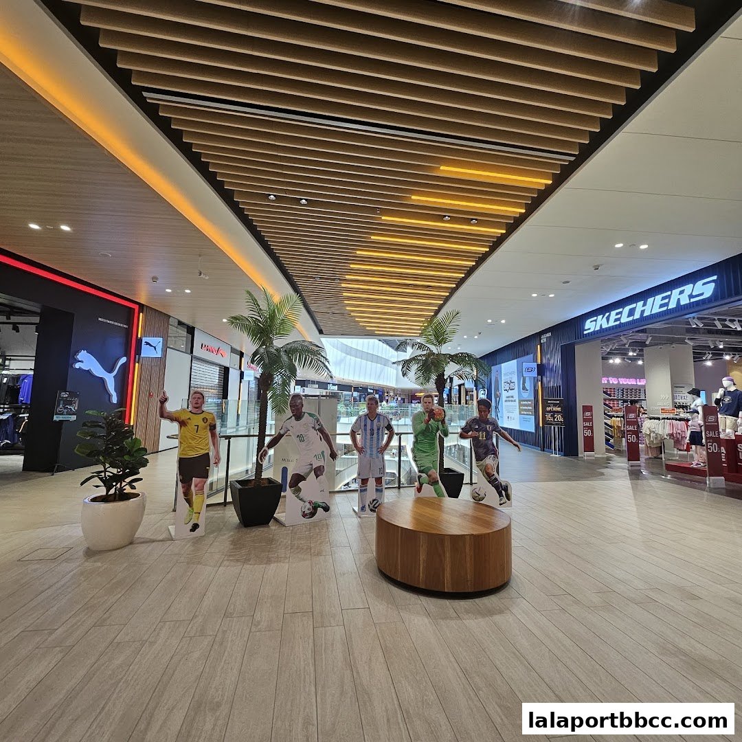 A shopping mall interior with Puma and Skechers stores, featuring football player cutouts and palm trees.