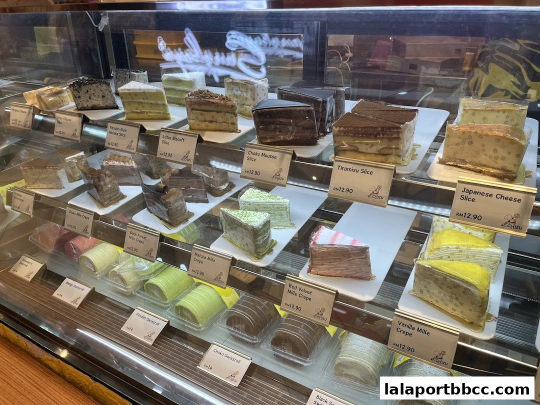 A display case filled with various slices of mille crepe cakes and swissrolls.