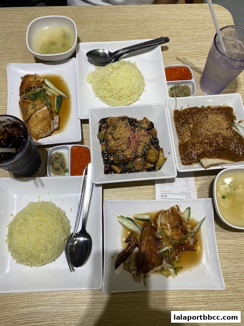 A table laden with delicious chicken rice meals, soup, and drinks.