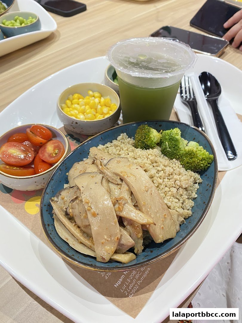 A healthy meal with quinoa, mushrooms, broccoli, corn, tomatoes, and a green drink.