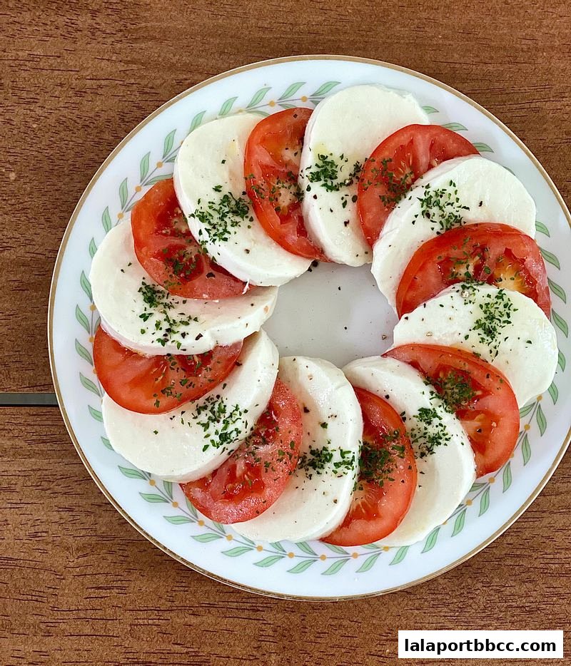 A plate of Caprese salad with sliced tomatoes and mozzarella cheese, garnished with herbs.