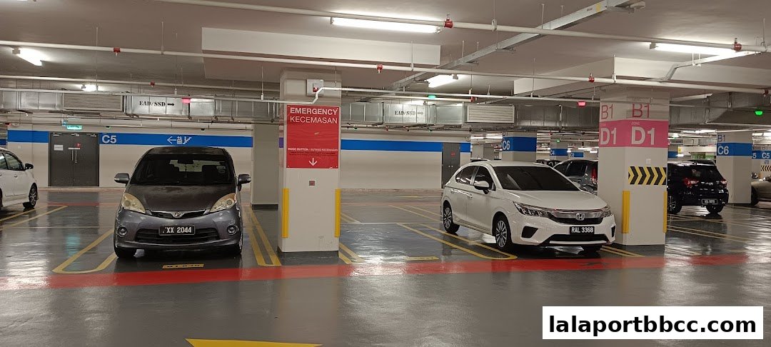 A parking garage with cars parked in designated spots, featuring directional signage and emergency information.