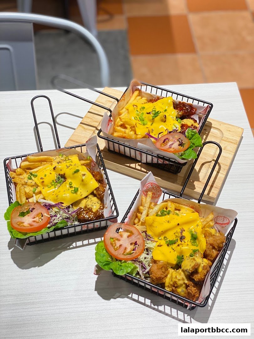Three baskets of loaded fries with cheese, chicken, and garnishes on a table.