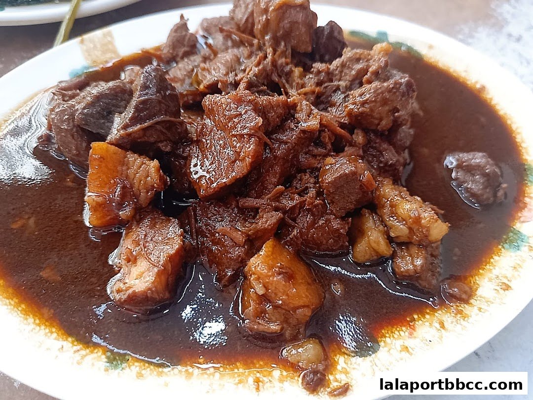 A close-up shot of tender braised beef and pork belly in a rich, dark sauce.