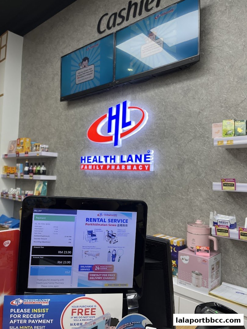 Interior view of a Health Lane Family Pharmacy with a cashier counter, digital screens, and products on shelves.