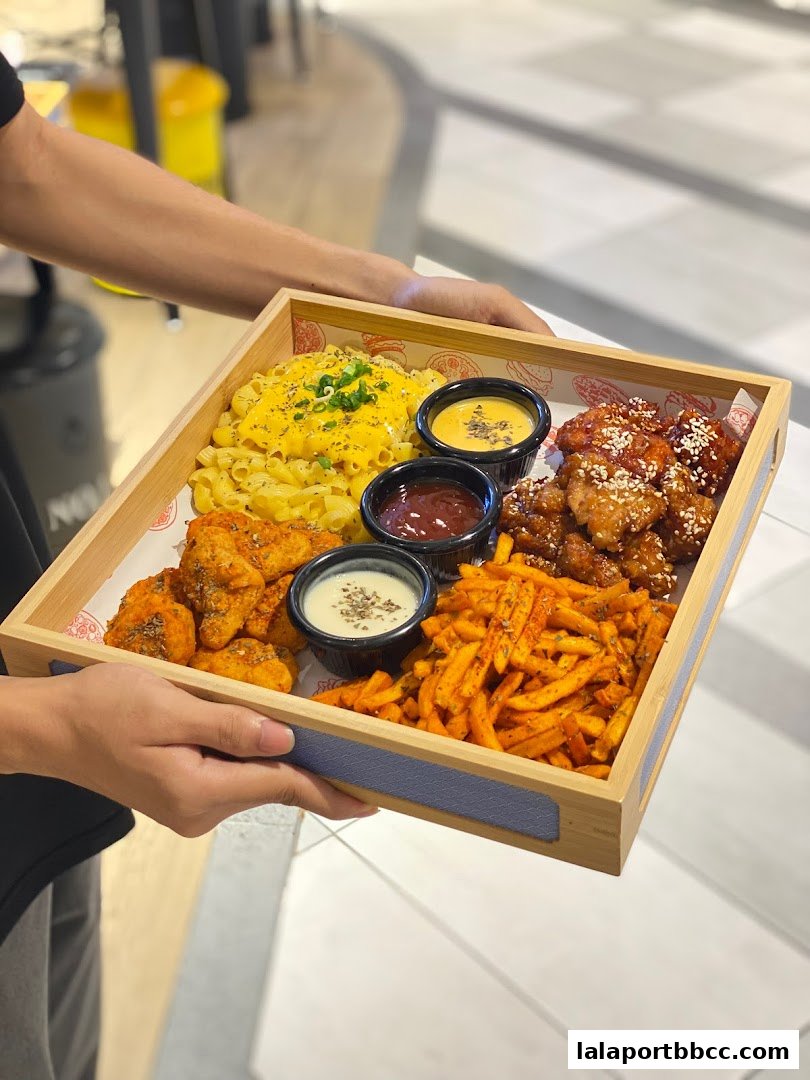 A platter of fried chicken, fries, pasta, and dipping sauces is presented.