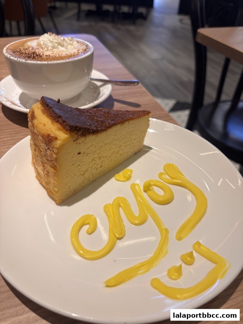 A slice of cheesecake with whipped cream coffee and the word 'enjoy' written in sauce.