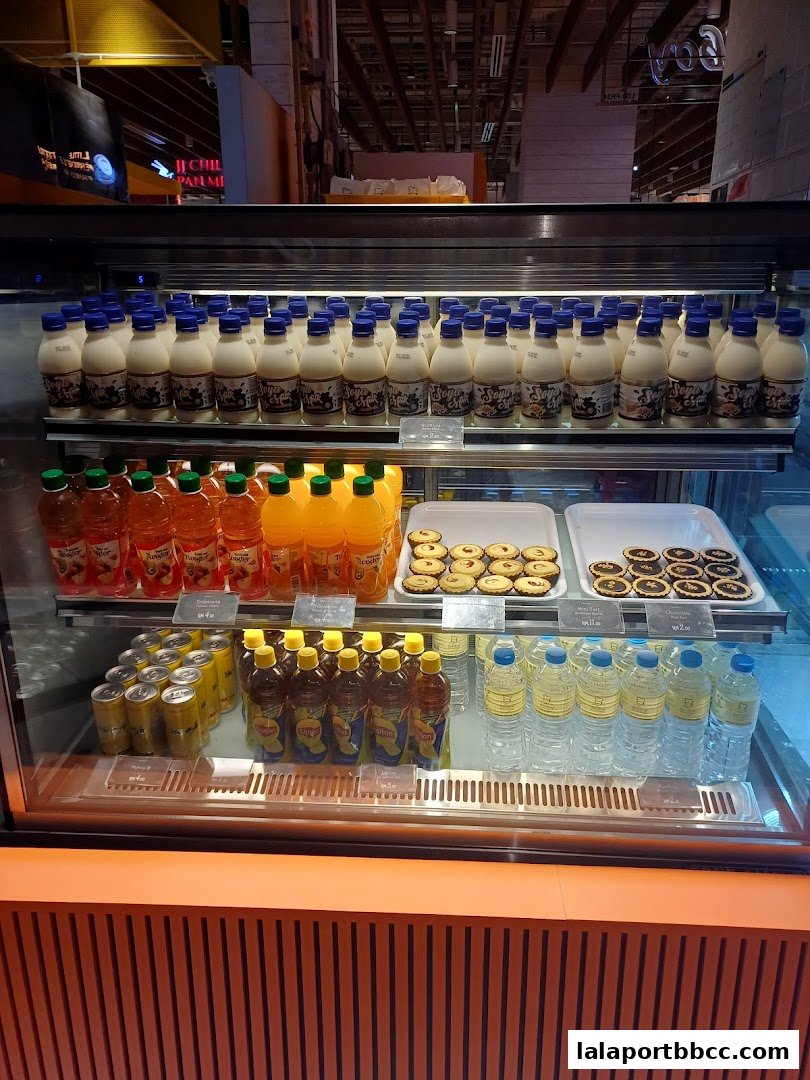 A display case filled with bottled drinks, canned beverages, and pastries.