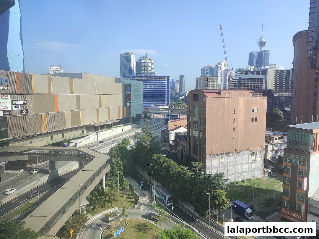 A cityscape view showing the Lalaport shopping mall and surrounding buildings under a clear sky.