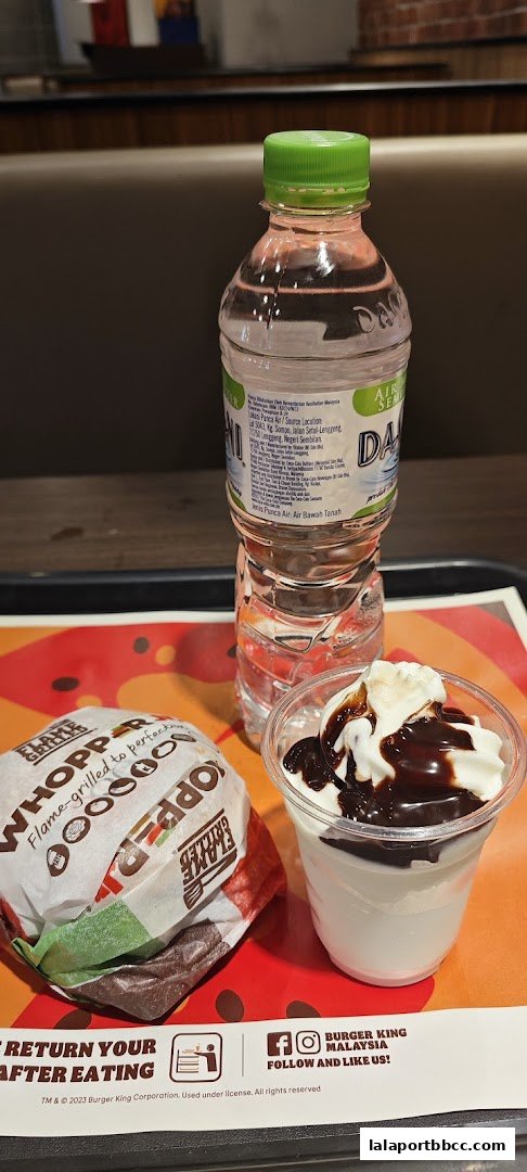 A Burger King Whopper meal with a bottle of water and a dessert cup.