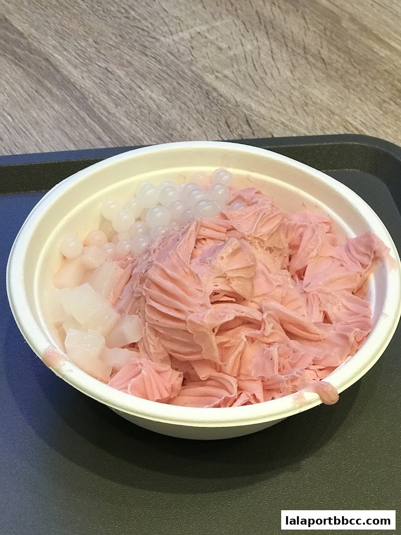 A bowl of pink shaved ice with tapioca pearls and white jelly.
