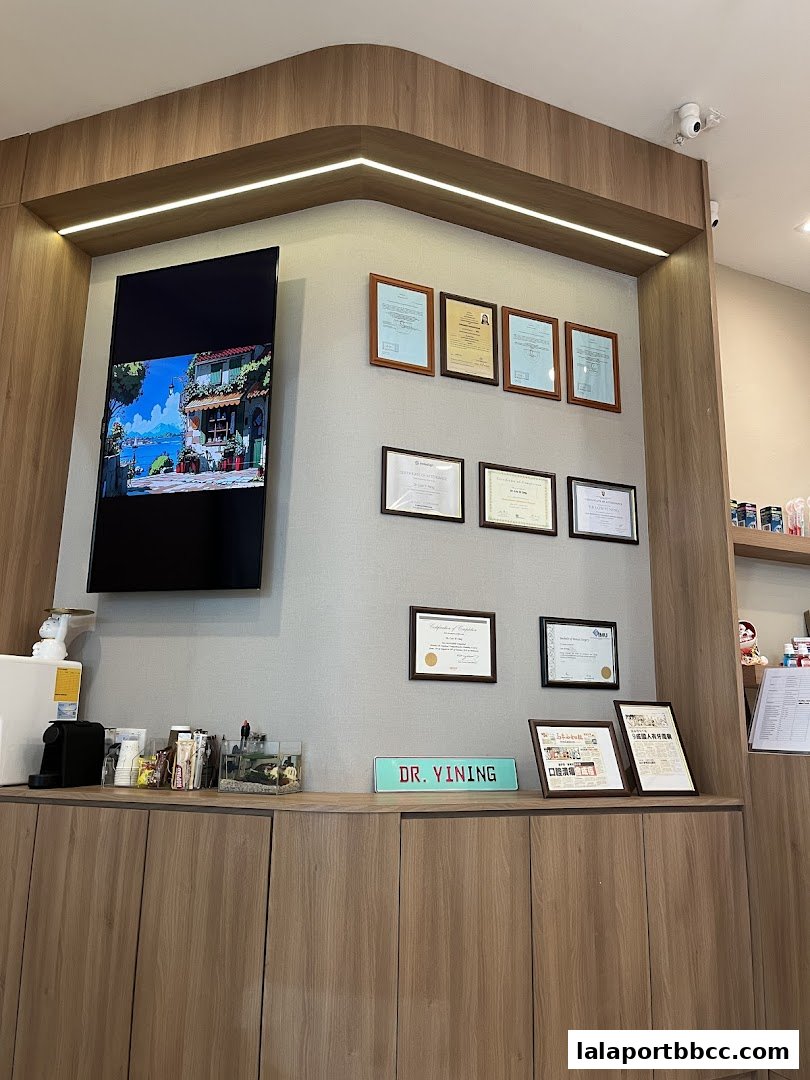 Interior shot of a dental clinic with framed certificates and a TV screen.