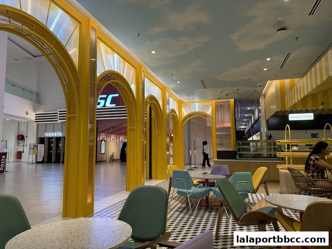 Interior view of a brightly decorated cafe with yellow arches and colorful chairs.