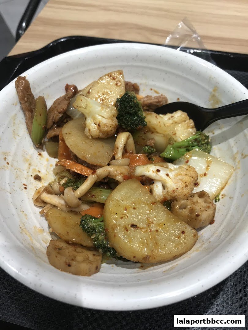 A bowl of stir-fried rice with vegetables and meat, seasoned with spices.