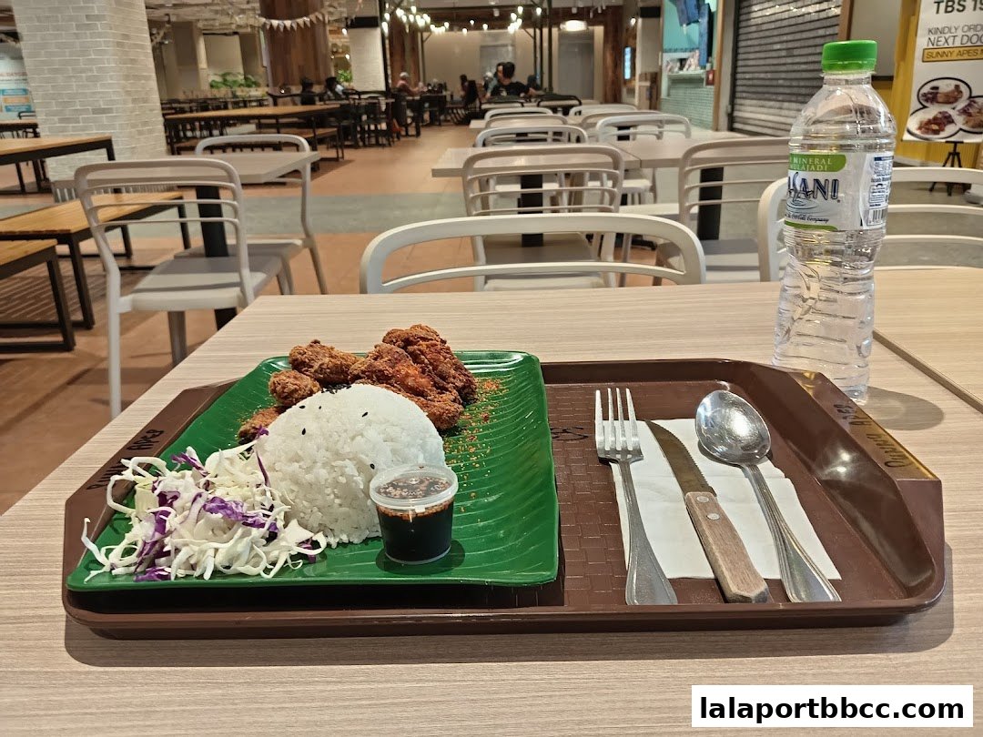 A tray of fried chicken with rice and salad, served with a bottle of water.