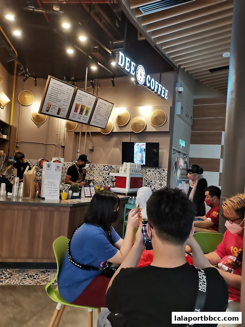 Customers sit at tables inside a coffee shop with a menu board visible.