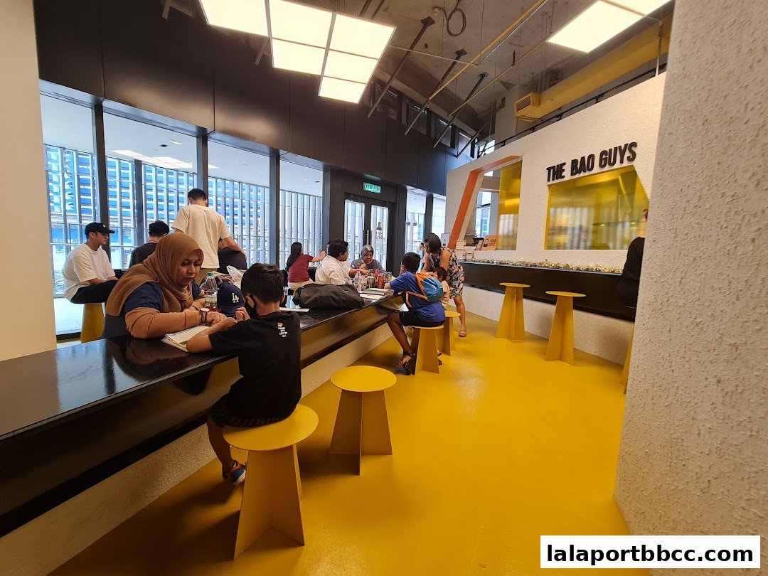 Interior view of The Bao Guys restaurant with customers seated at a counter and yellow stools.