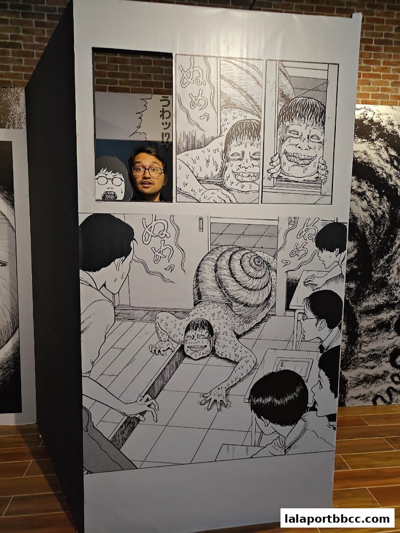 A person peeks through a window of a display featuring Junji Ito manga panels.