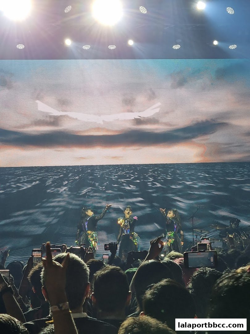 Performers on stage with a large screen displaying a sunset over the ocean.