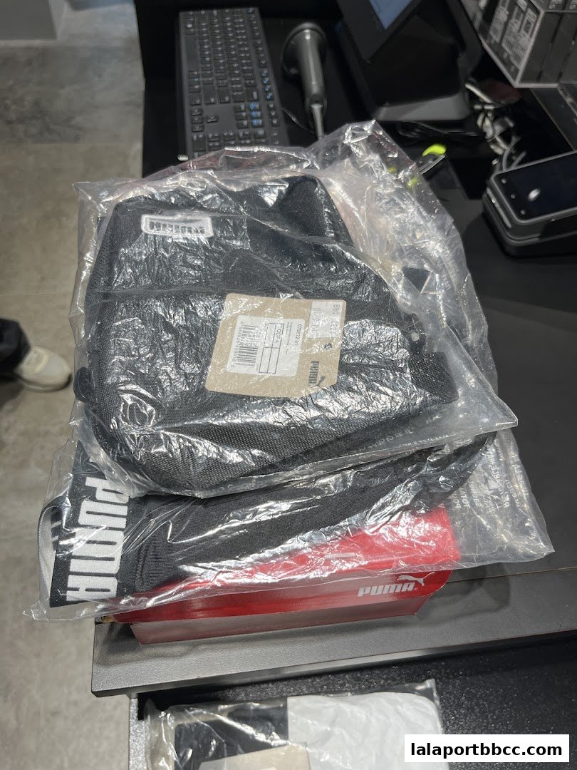 Puma branded bags and a red item packaged in plastic on a counter.