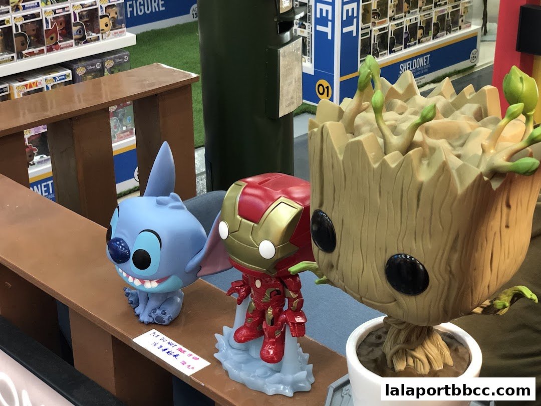 Three large collectible figures, Stitch, Iron Man, and Groot, displayed on a shelf in a toy store.