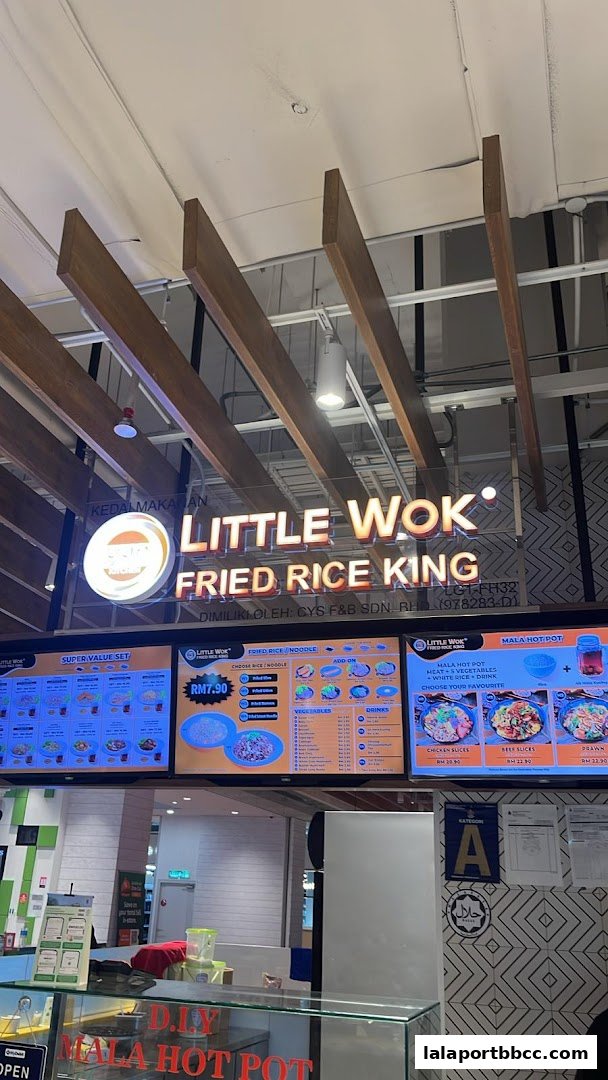 A food stall with a large illuminated sign and digital menus displaying various dishes and prices.