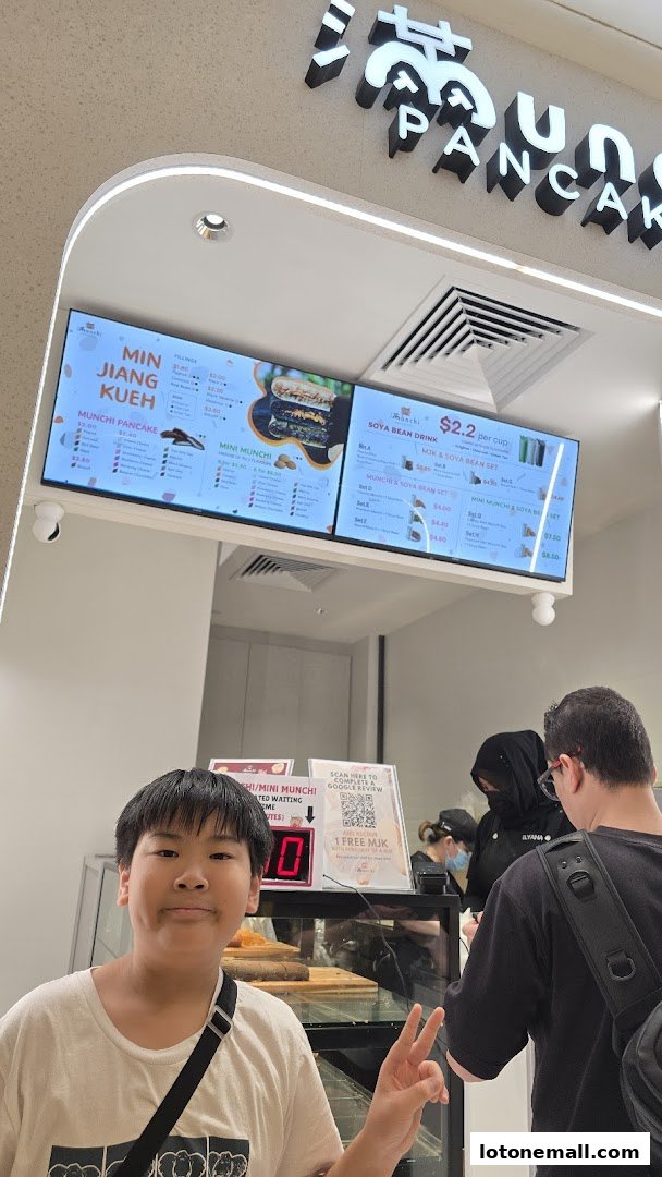 A digital menu board displays various pancake and drink options at Munchi Pancakes.