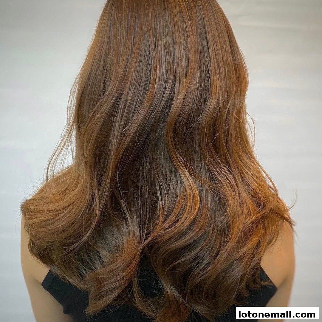 A person's back with long, wavy, brown hair with subtle highlights.