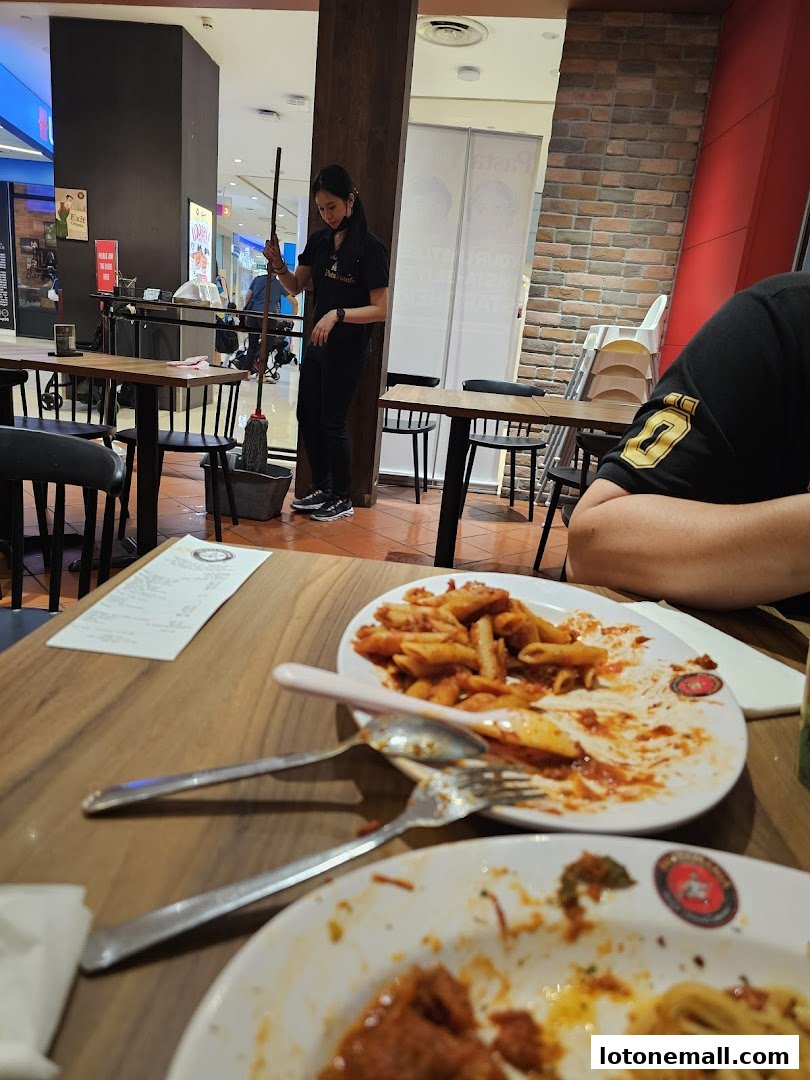 A staff member mops the floor while diners enjoy pasta at PastaMania.