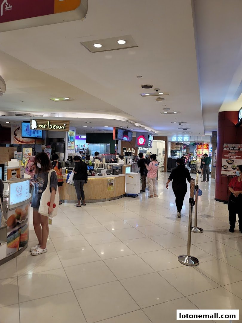 People queuing at various food stalls and shops inside a mall.