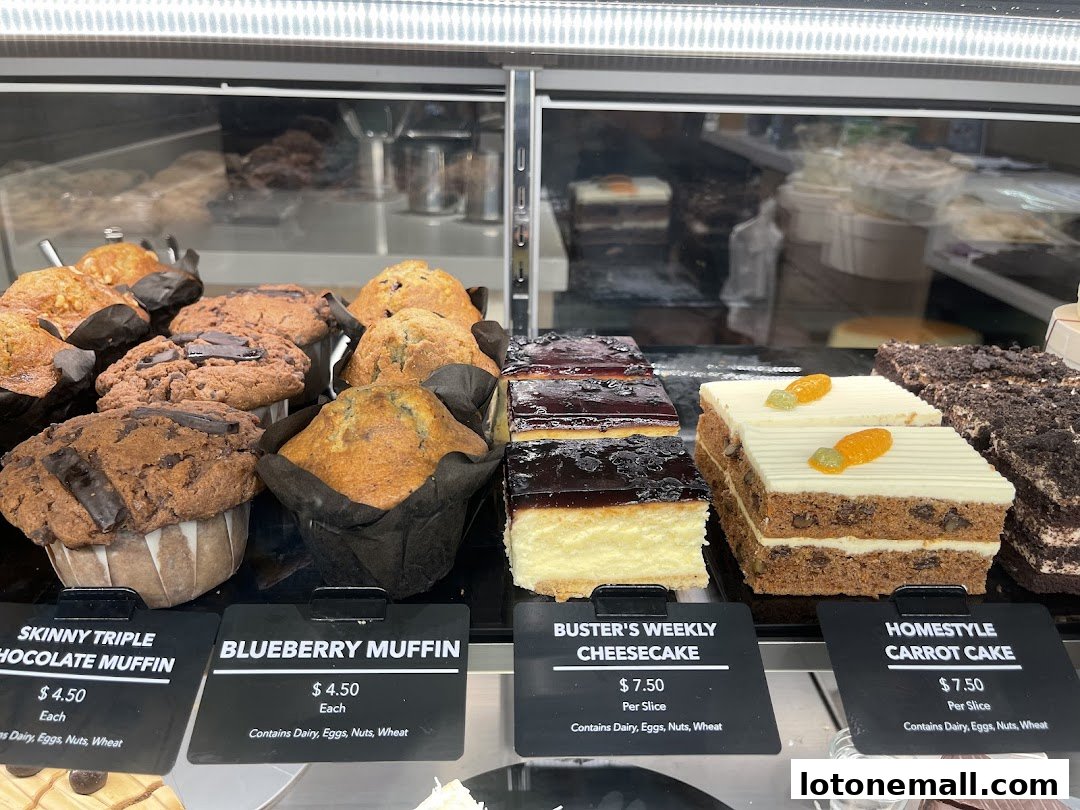A display case filled with various muffins, cheesecakes, and cakes.