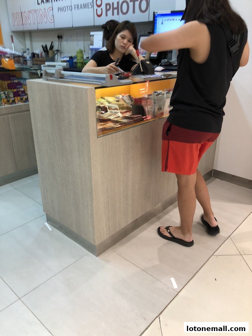 A customer interacts with a staff member at the Kodak Express counter, which displays various products.
