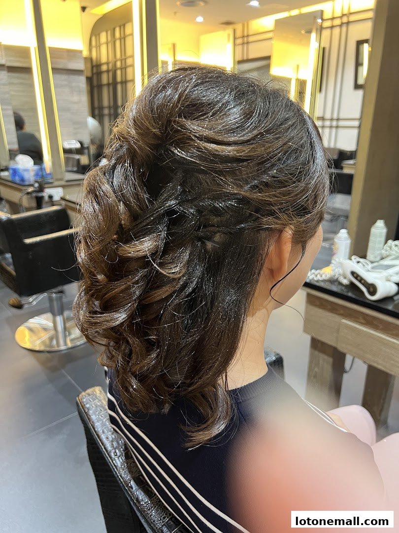 A woman with a stylish braided updo with glittery highlights at a salon.