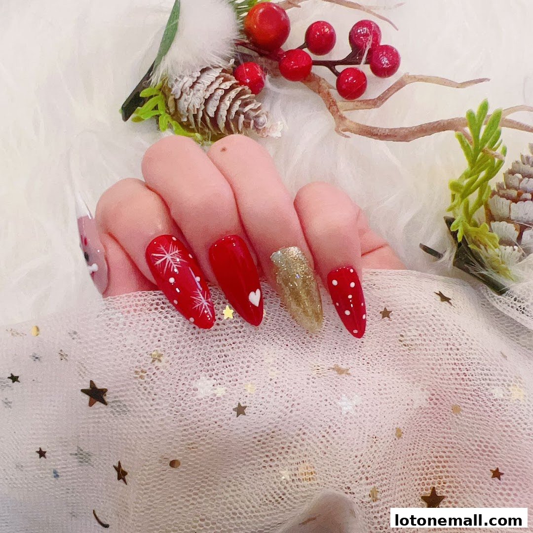 A hand with festive red and gold nails decorated with snowflakes and polka dots.