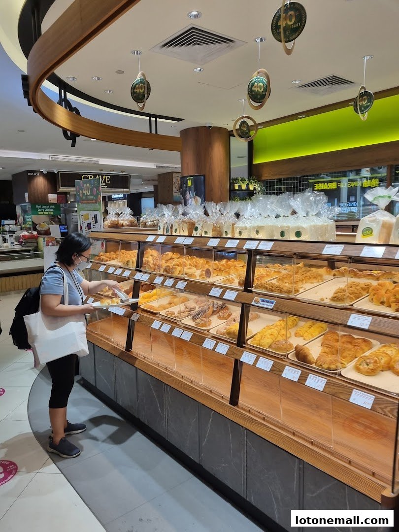 A customer selects pastries from a display case filled with baked goods at a bakery.
