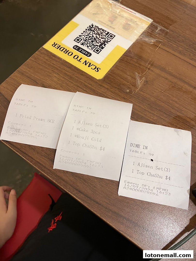 Receipts and a QR code for ordering on a wooden table at Ajisen Ramen.