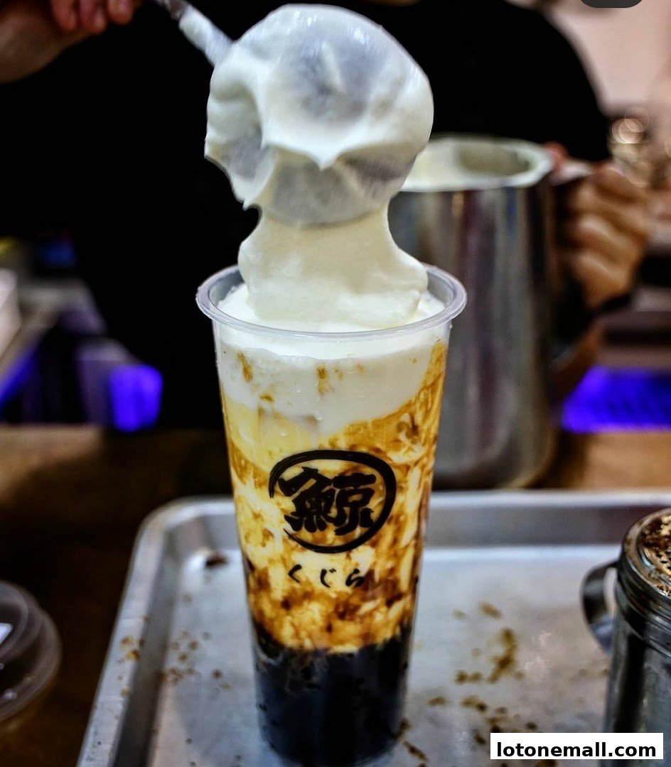 A close-up of a creamy brown sugar bubble tea being prepared with a thick layer of foam.