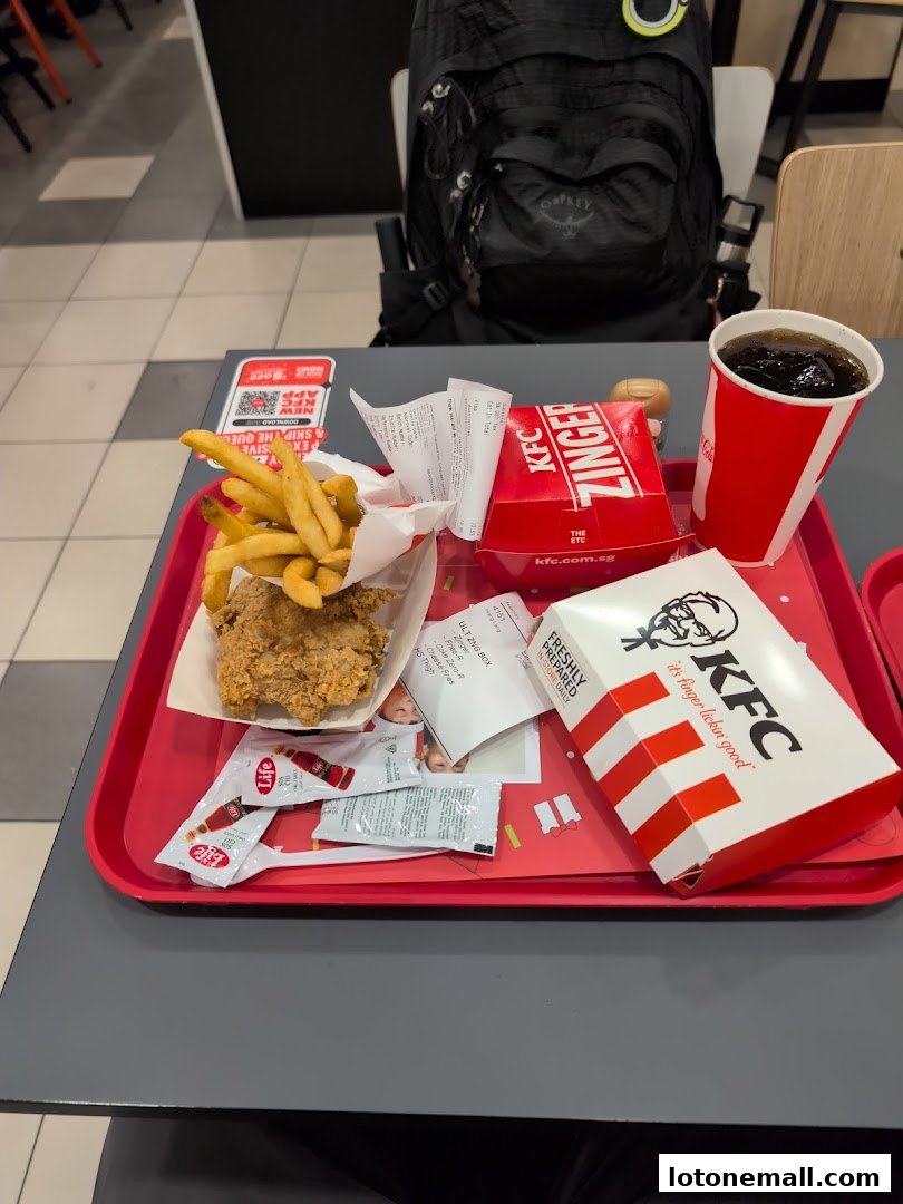 A tray of KFC food including fried chicken, fries, a drink, and a Zinger box.
