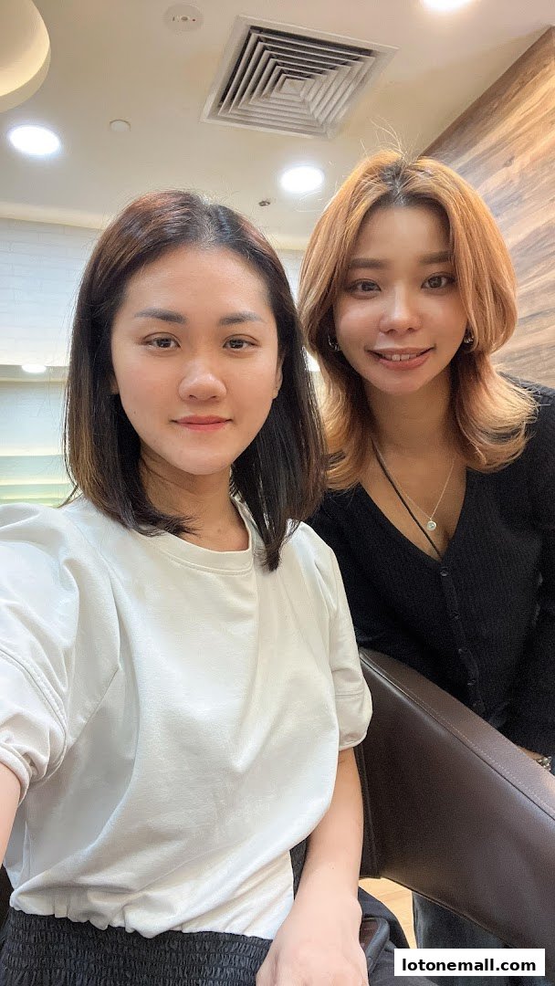 Two smiling women posing for a selfie in a hair studio.