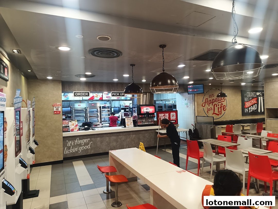 Interior view of a KFC restaurant with ordering counters, seating, and promotional posters.