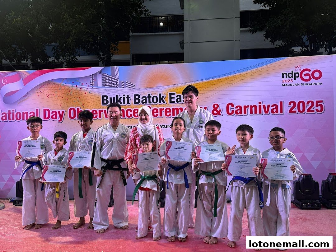 A group of children and adults in martial arts uniforms holding certificates at an event.