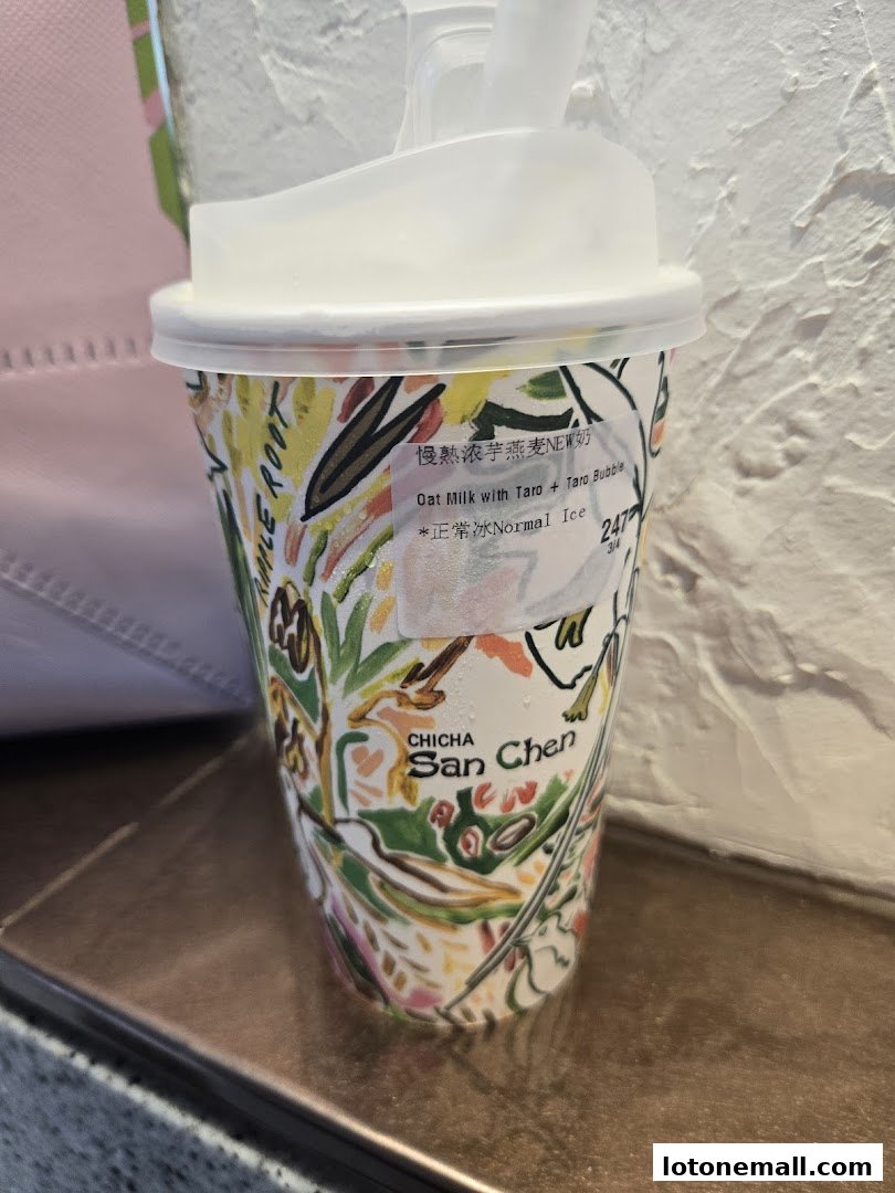 A close-up of a CHICHA San Chen cup with a colorful floral design, showing a drink with taro and oat milk.