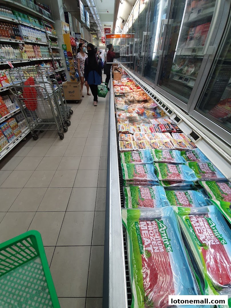 A grocery store aisle with chilled meat products and shelves stocked with various goods.