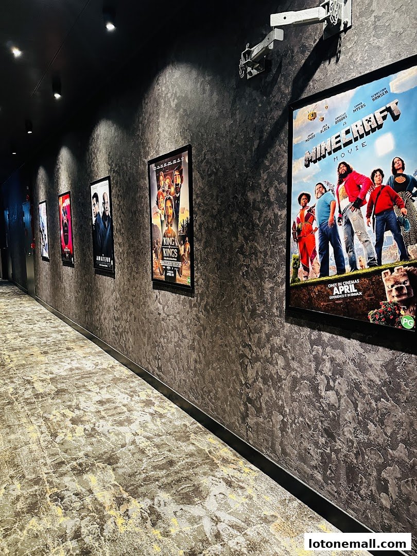 A hallway in a cinema with movie posters on the wall and a projector mount.