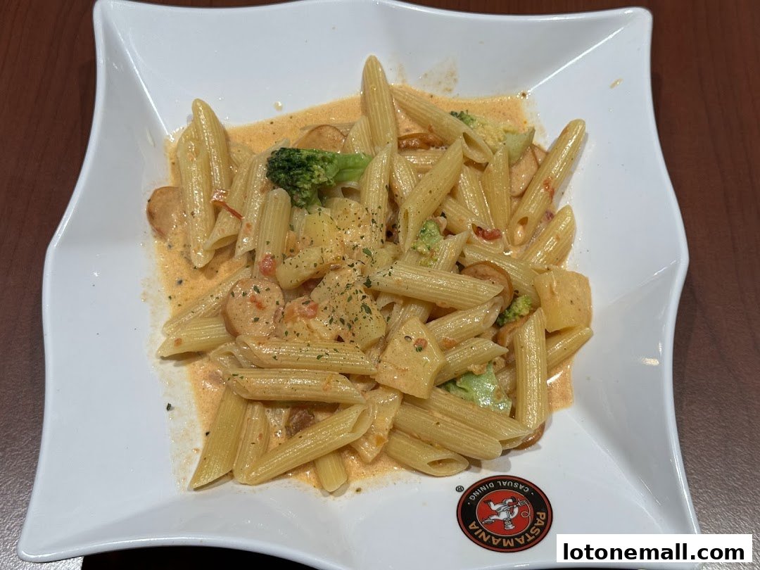 A plate of penne pasta with creamy sauce, broccoli, sausage, and potatoes.