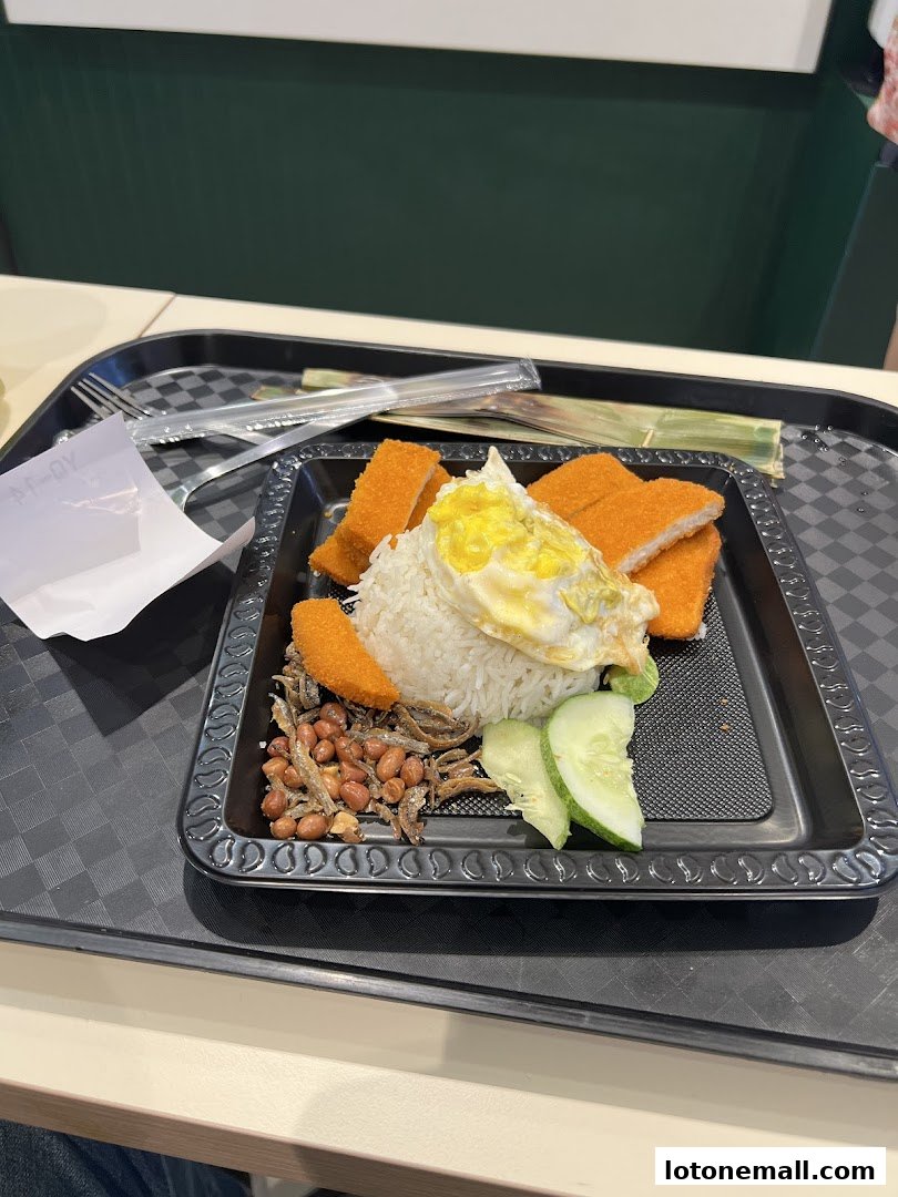A plate of Nasi Lemak with fried chicken, egg, peanuts, anchovies, and cucumber.