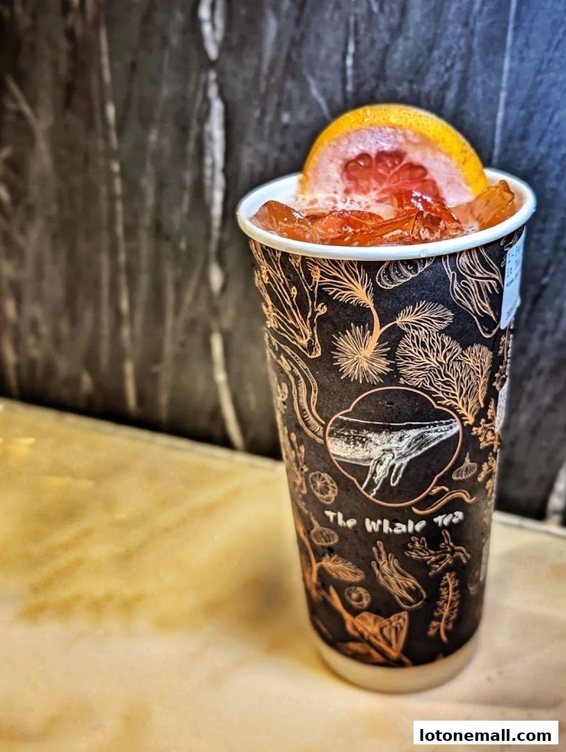 A refreshing drink with grapefruit slice and ice in a branded cup.