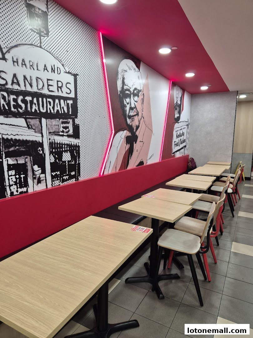 Interior of a KFC restaurant with tables, chairs, and wall art featuring Colonel Sanders.